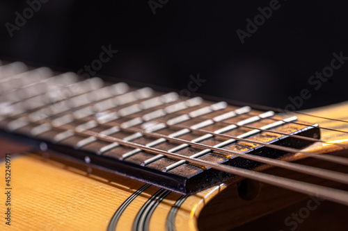 Close-up of a guitar fretboard on a black background.
