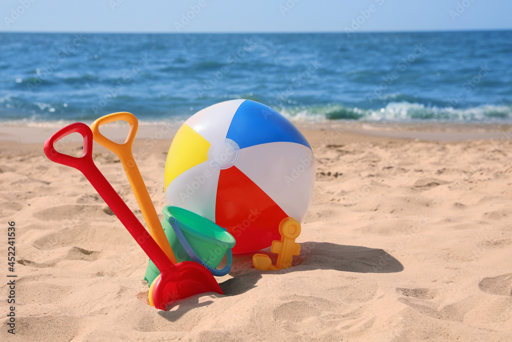 Obraz premium Different sand toys and beach ball near sea