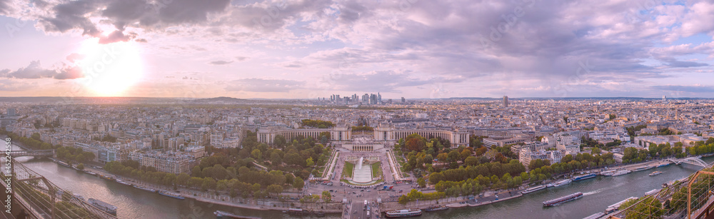A panoramic sunset view of Paris, centered on the Jardins de Trocadero and Palais de Chaillot, with the Seine River in the foreground, taken from atop the Eiffel Tower.