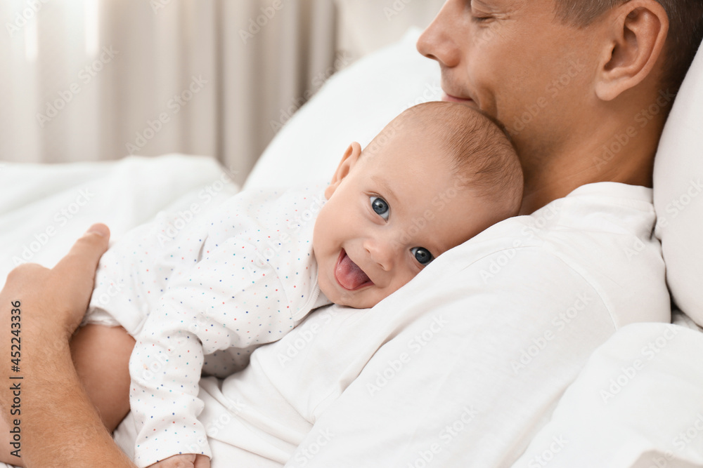 Father holding his cute baby on bed at home, closeup Father holding his cute baby on bed at home, closeup