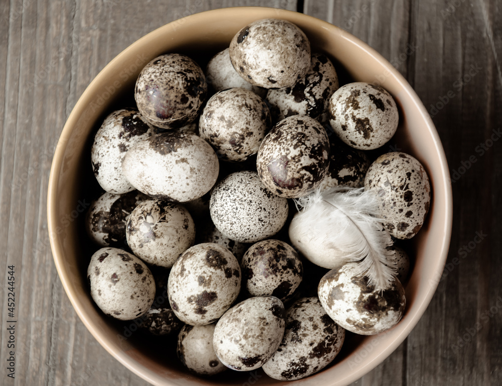 Quail eggs in bowl on background of an old wooden shield. Black and white photo. Agricultural products. Healthy dietary nutrition Quail eggs in bowl on background of an old wooden shield. Black and white photo. Agricultural products. Healthy dietary nutrition