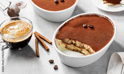 Classic Italian Dessert Tiramisu topped with cocoa  in a ceramic dish. Light gray background.