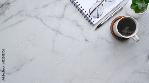 Top view notebook, coffee cup and glasses on marble background.