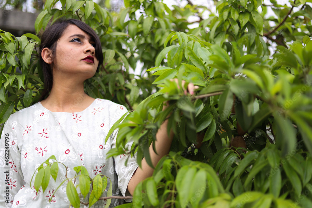 A brown young woman holding green leaves of a tree -symbolizing the love for our nature -with space to write your text A brown young woman holding green leaves of a tree -symbolizing the love for our nature -with space to write your text