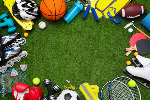 Frame of different sport equipment on green grass, flat lay. Space for text © New Africa