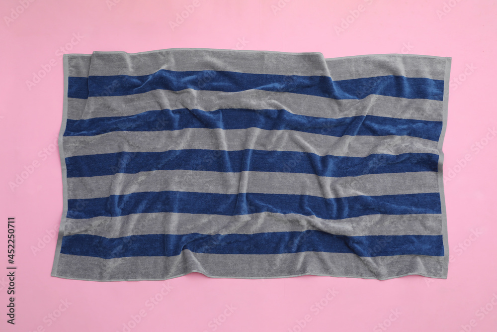 Crumpled striped beach towel on pink background, top view Crumpled striped beach towel on pink background, top view