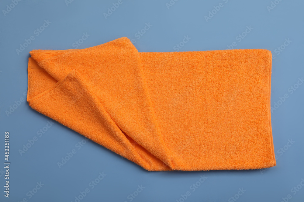 Folded orange beach towel on blue background, top view Folded orange beach towel on blue background, top view