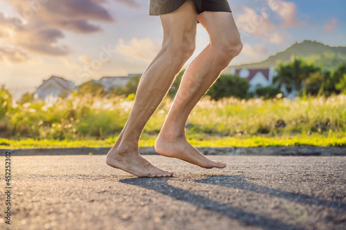 A man runner is engaged in jogging on the asphalt without shoes, without sneakers, for health