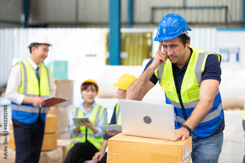 engineer or factory worker using laptop computer and thinking of something seriously in warehouse storage engineer or factory worker using laptop computer and thinking of something seriously in warehouse storage