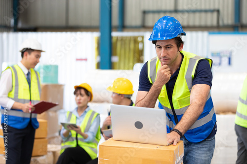 engineer or factory worker using laptop computer and thinking of something seriously in warehouse storage
