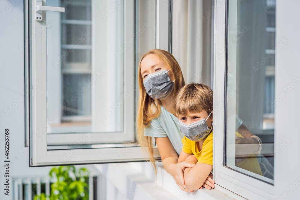 Extremly tired Mother and son looking out the window, home alone. self-isolation at home, quarantine due to pandemic COVID 19. Mental health problems in self-isolation at home, quarantine, isolation Extremly tired Mother and son looking out the window, home alone. self-isolation at home, quarantine due to pandemic COVID 19. Mental health problems in self-isolation at home, quarantine, isolation