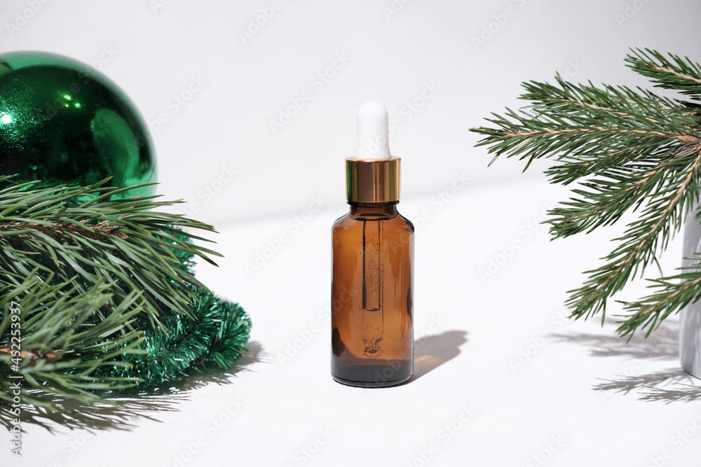 Fototapeta premium Christmas minimalistic composition with amber glass serum or oil bottle . skin health and beauty concept