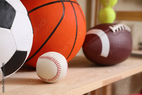 Different sport balls on wooden shelf  closeup