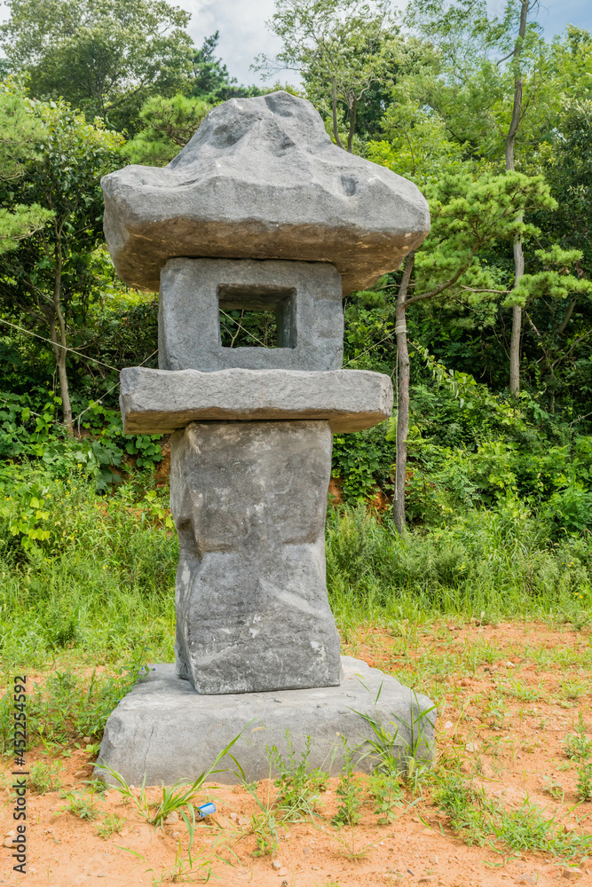 Large stone carved lantern beside concrete walkway in rural public park. Large stone carved lantern beside concrete walkway in rural public park.