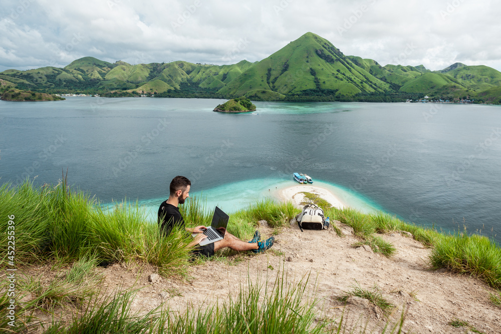 A man with a laptop working remotely on the tropical island A man with a laptop working remotely on the tropical island