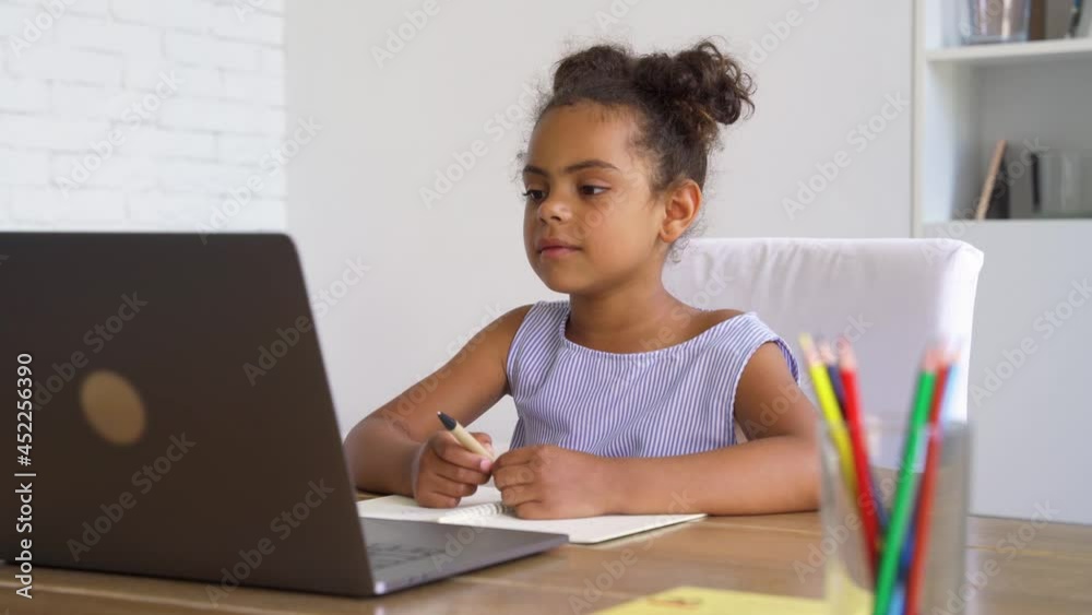 African american elementary school girl studying online at home using laptop African american elementary school girl studying online at home using laptop