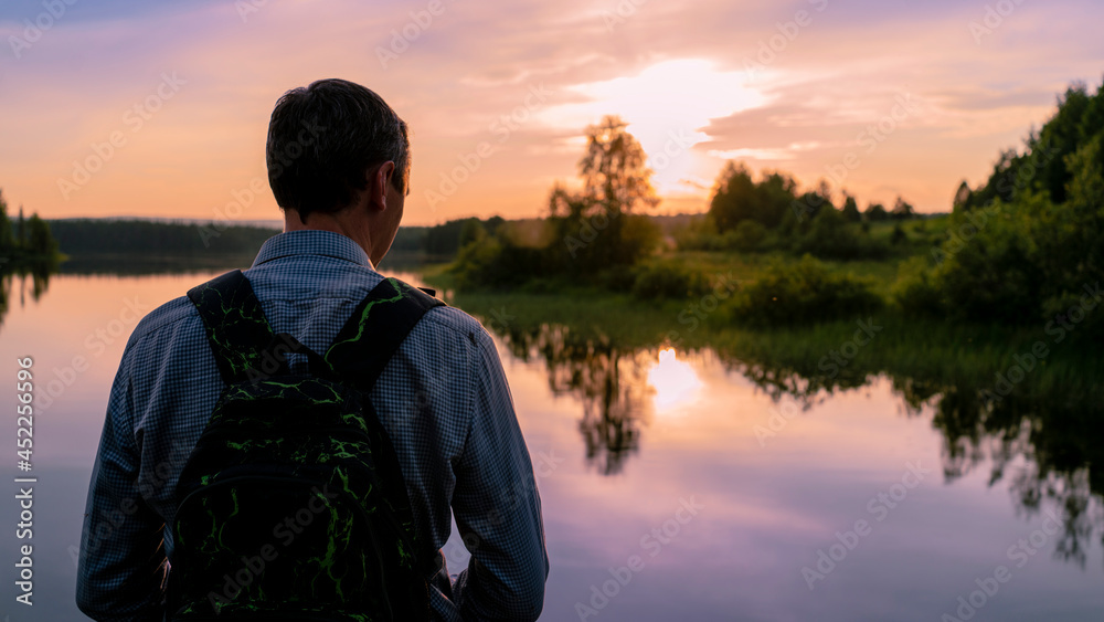 Tourist looking at the lake. Sunset in the evening with rim light effect during sunset. The concept of travel and pleasant outdoor recreation. Tourist looking at the lake. Sunset in the evening with rim light effect during sunset. The concept of travel and pleasant outdoor recreation.