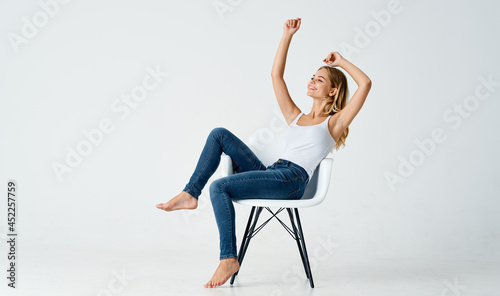 attractive woman sitting on a chair in jeans movement emotions posing