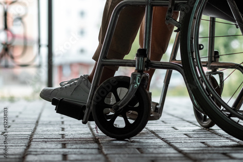 Close-up of a leg on a wheelchair in the street. Disease recognition, disability, serious condition.
