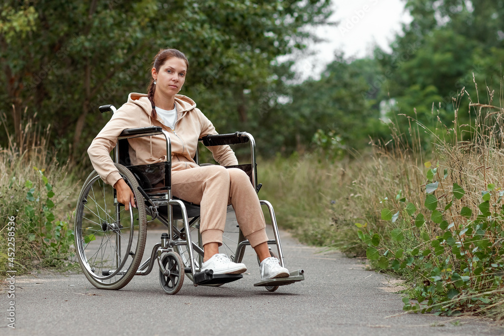 A young disabled girl sits in a wheelchair on the street. The concept of a wheelchair, disabled person, full life, paralyzed, disabled person, health care.