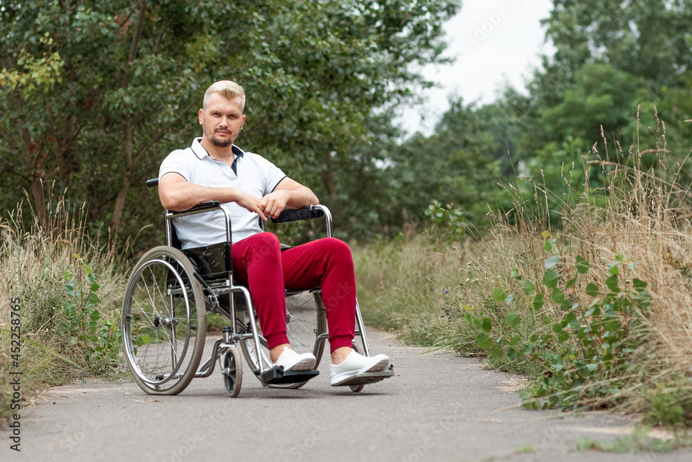 A disabled man sits in a wheelchair on the street. The concept of a wheelchair, disabled person, full life, paralyzed, disabled person, health care.
