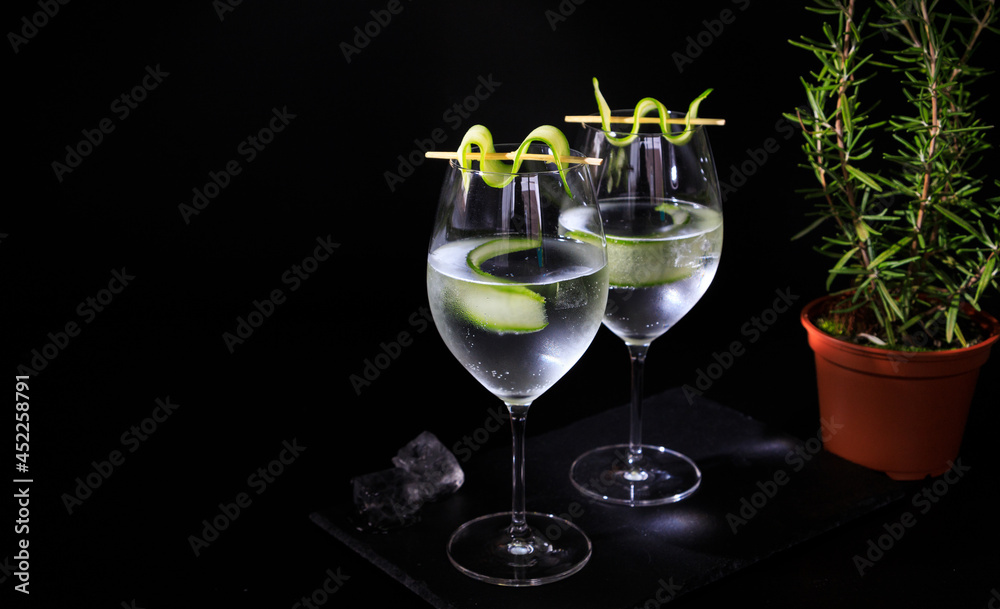 two gin tonc with cucumber and rosemary on a balck background