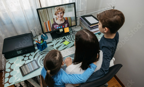 Top view of mother and children talking on video call with computer with grandmother