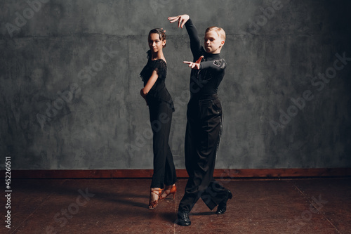 Couple young man and woman in black dress dancing in ballroom dance rumba