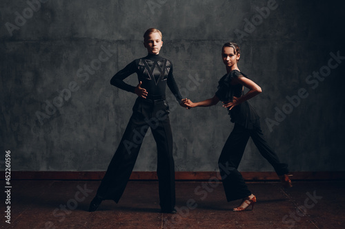 Couple in black costumes dancing in ballroom rumba dance
