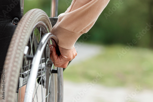 Close-up of a hand on a wheelchair wheel. The concept of a wheelchair, disabled person, full life, paralyzed, disabled person, happy life.