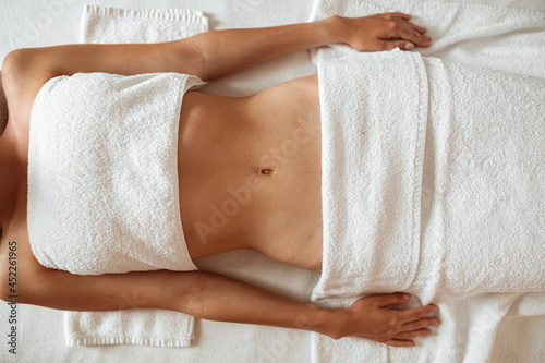 Fit young woman lying on massage table in spa salon