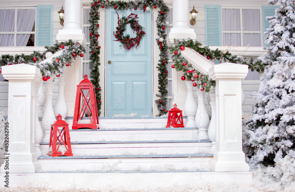 Fototapeta premium Christmas porch.Snowy courtyard with Christmas porch, veranda, wreath, Christmas tree, garland,christmas balls and lanterns. Merry Christmas and Happy New Year