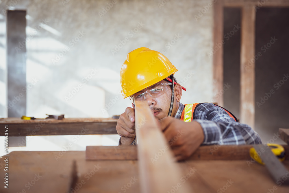 Young Asian carpentry worker in a workshop Work on the roof structure of a wooden house at a construction site. Young Asian carpentry worker in a workshop Work on the roof structure of a wooden house at a construction site.
