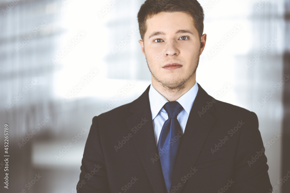 Young businessman wearing suit and tie, while standing in the office. Business success concept nowadays Young businessman wearing suit and tie, while standing in the office. Business success concept nowadays