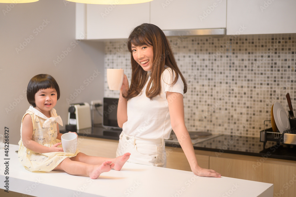 Portrait of happy mom and daughter in kitchen at home Portrait of happy mom and daughter in kitchen at home