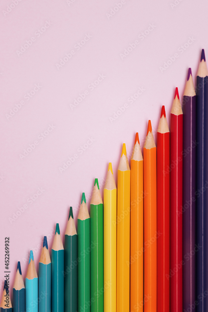 Colored pointed pencils lie on a pink background with space for copying. School supplies or school preparation. Top view. Colored pointed pencils lie on a pink background with space for copying. School supplies or school preparation. Top view.