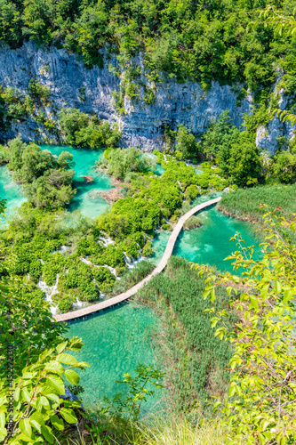 Aerial view of wooden footpath trail at Plitvice lakes, Croatia. Tourist path above blue lagoon near the waterfalls. Empty bridge without peoples.