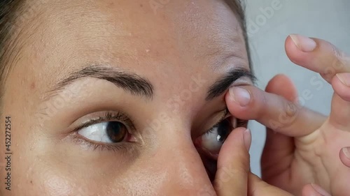 The brunette puts on contact lenses on her eye, holding her finger. Treating eye conditions such as myopia or myopia, astigmatism, or cosmetic lenses. Improvement and correction of vision. photo