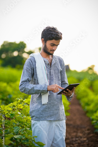 Young indian farmer using tablet and giving expression at cotton field