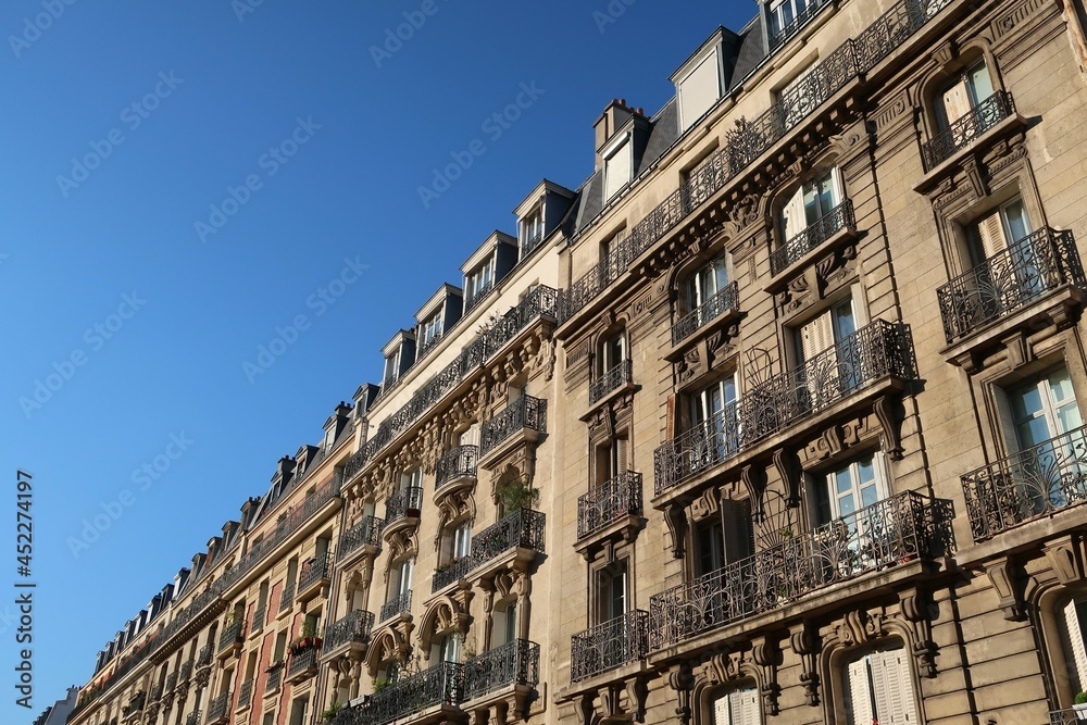 Immobilier ancien dans la ville de Paris, alignement de façades d'immeubles haussmanniens avec balcons, sur fond de ciel bleu (France)