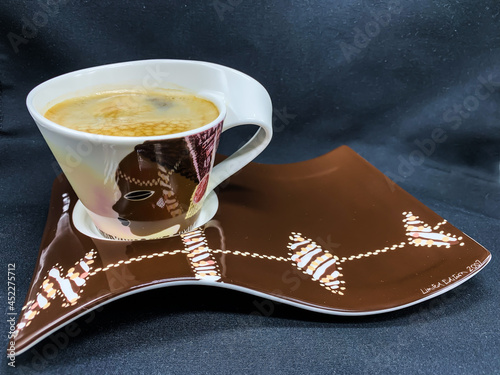 A cup of coffee on a saucer on a dark background
