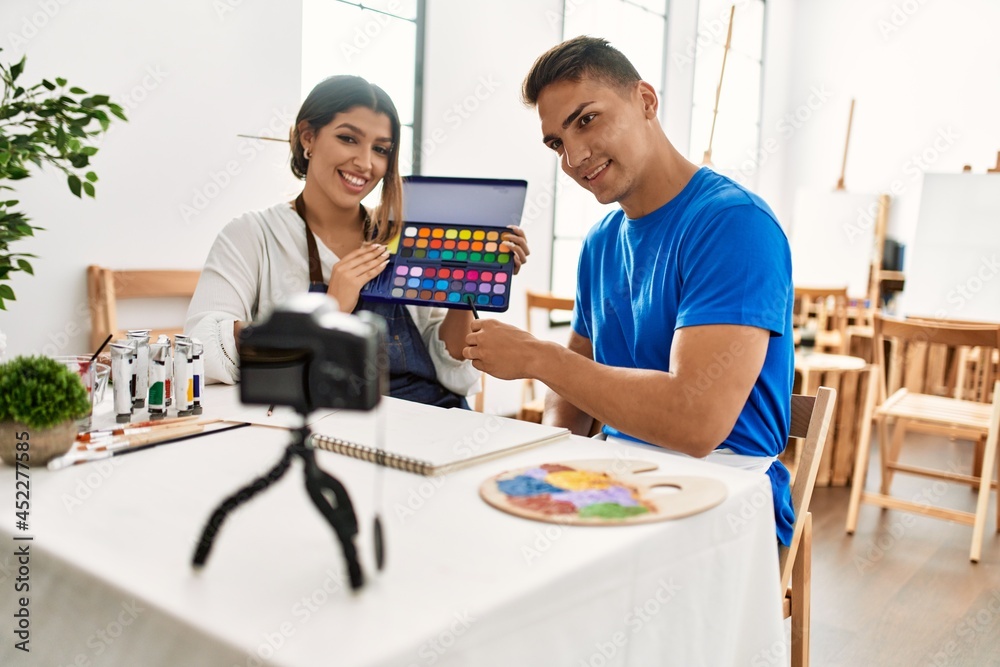 Two students smiling happy recording paint class using camera at art school. Two students smiling happy recording paint class using camera at art school.