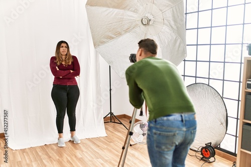 Young woman at photography studio skeptic and nervous, disapproving expression on face with crossed arms. negative person.