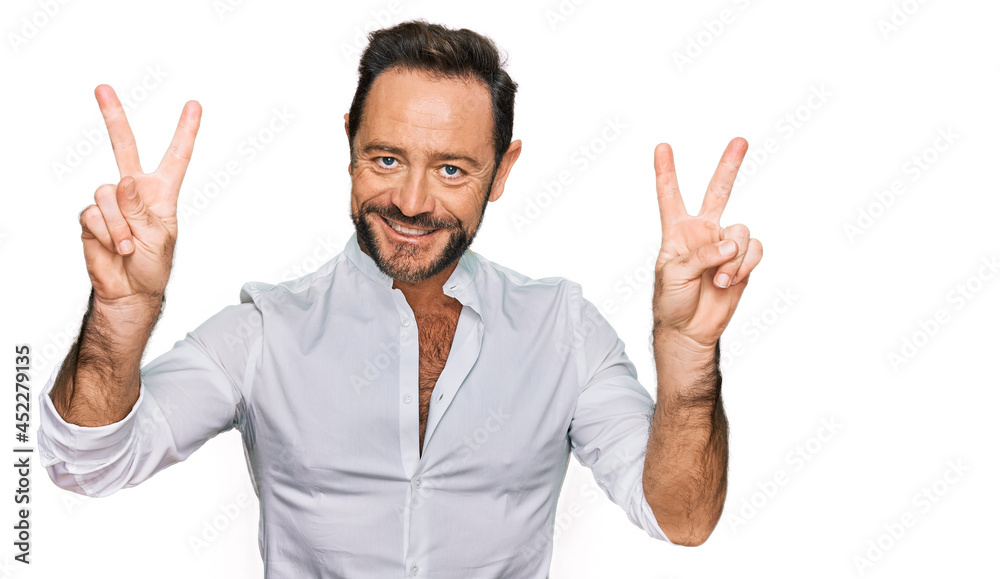 Middle age man wearing casual clothes smiling looking to the camera showing fingers doing victory sign. number two. Middle age man wearing casual clothes smiling looking to the camera showing fingers doing victory sign. number two.