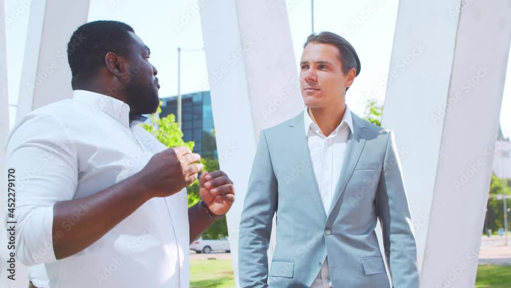 Confident African-American businessman and his colleague in front of modern office building. Financial investors are talking outdoor. Banking and business.