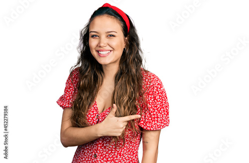 Young hispanic girl wearing casual clothes cheerful with a smile of face pointing with hand and finger up to the side with happy and natural expression on face