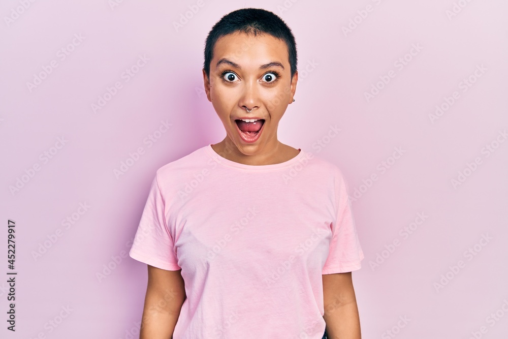 Beautiful hispanic woman with short hair wearing casual pink t shirt afraid and shocked with surprise and amazed expression, fear and excited face. Beautiful hispanic woman with short hair wearing casual pink t shirt afraid and shocked with surprise and amazed expression, fear and excited face.
