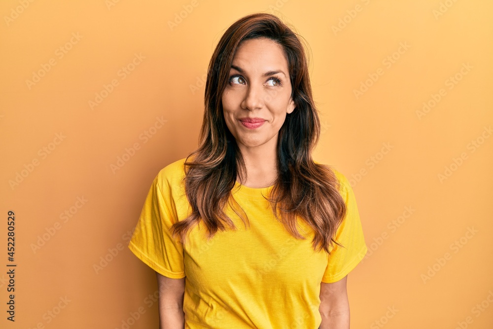 Young latin woman wearing casual clothes smiling looking to the side and staring away thinking. Young latin woman wearing casual clothes smiling looking to the side and staring away thinking.