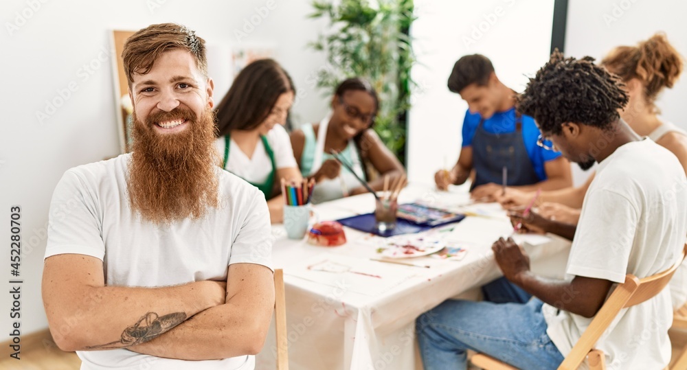 Fototapeta premium Group of people drawing sitting on the table. Caucasian man smiling happy looking to the camera at art studio.