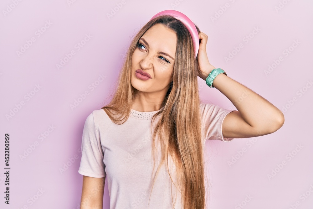 Young blonde girl wearing casual clothes confuse and wondering about question. uncertain with doubt, thinking with hand on head. pensive concept. Young blonde girl wearing casual clothes confuse and wondering about question. uncertain with doubt, thinking with hand on head. pensive concept.